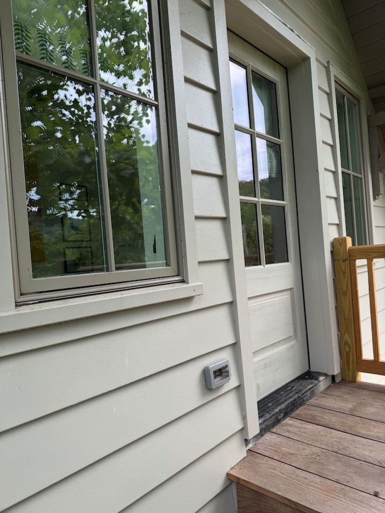 A house with large windows, a wooden bench, and a small outdoor area.