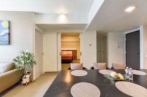 Una habitación de hotel moderna con una mesa de comedor, un sofá y una planta en maceta.