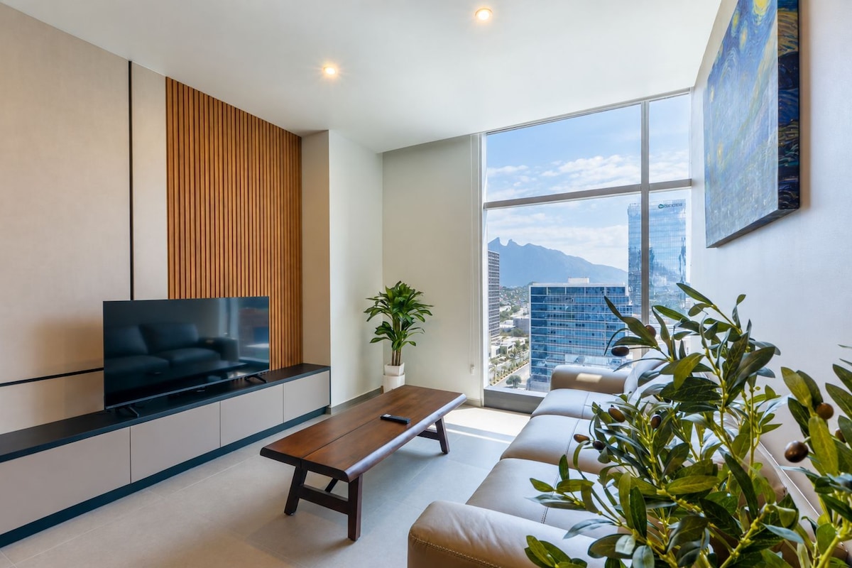 Una sala de estar moderna con un televisor de pantalla plana, un panel de pared de madera, un ventanal con vista a la ciudad y una planta en maceta.