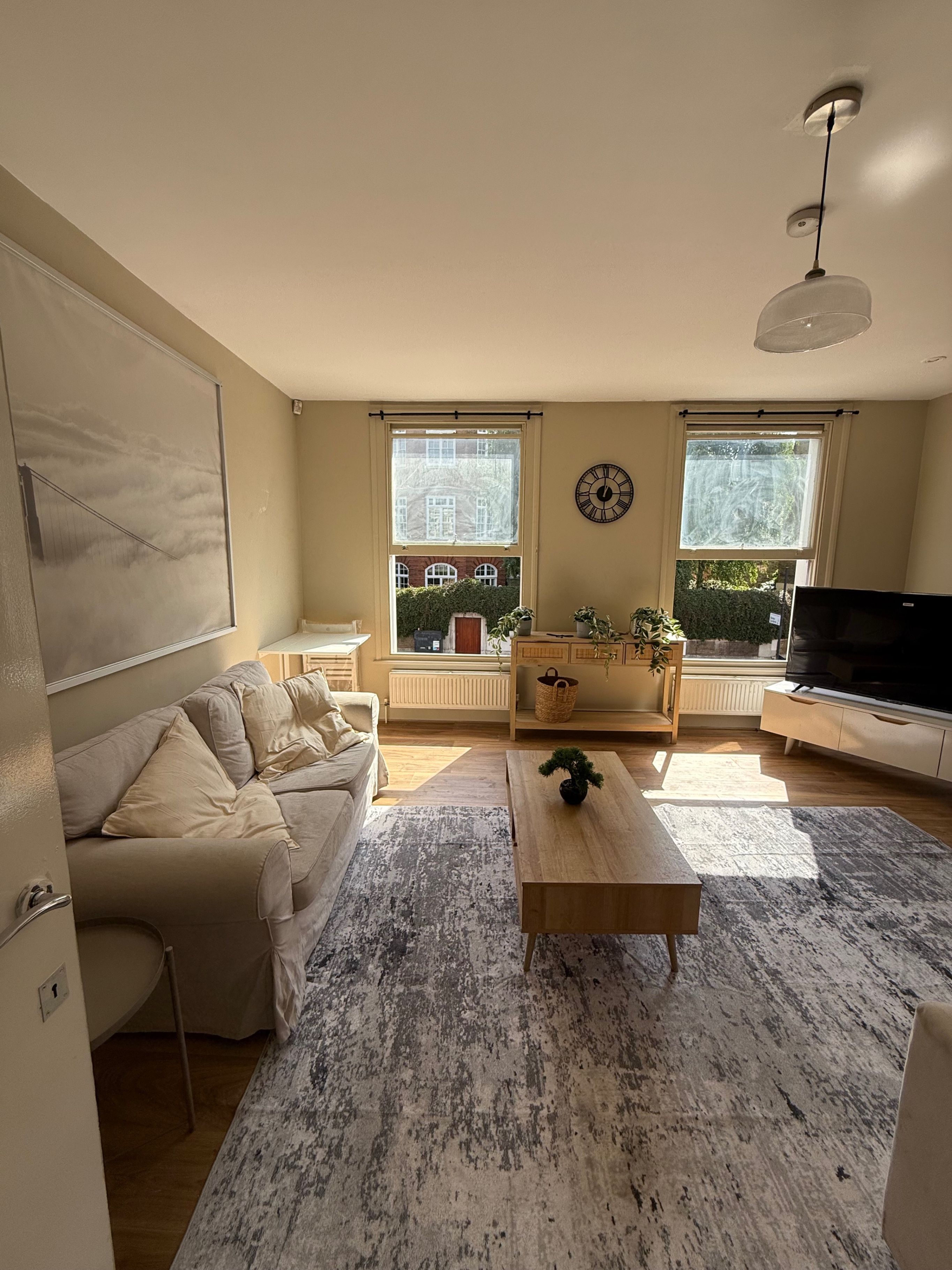 A living room with a sofa, coffee table, TV, and windows.