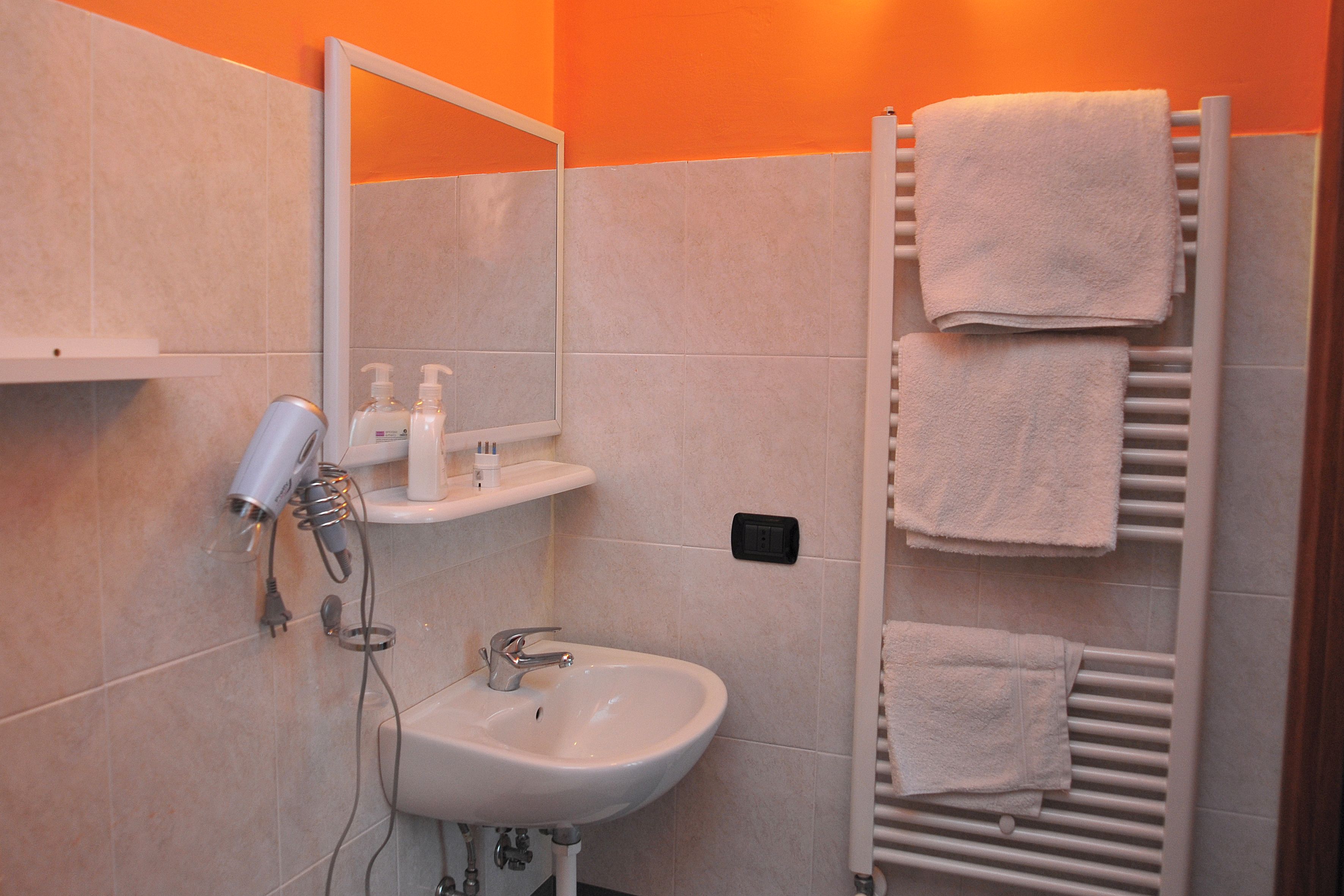 Un bagno con lavandino, specchio, asciugamano e asciugacapelli.
