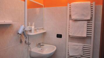 Un bagno con lavandino, specchio, asciugamano e asciugacapelli.