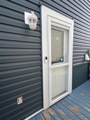 A door with a glass panel, a white door frame, and a small outdoor light fixture above it. - Pristine Spacious for Groups in Yeg|4mins to Wem (Edmonton)