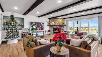 A modern living room with a fireplace, leather sofas, a Christmas tree, and a view of the outdoors.