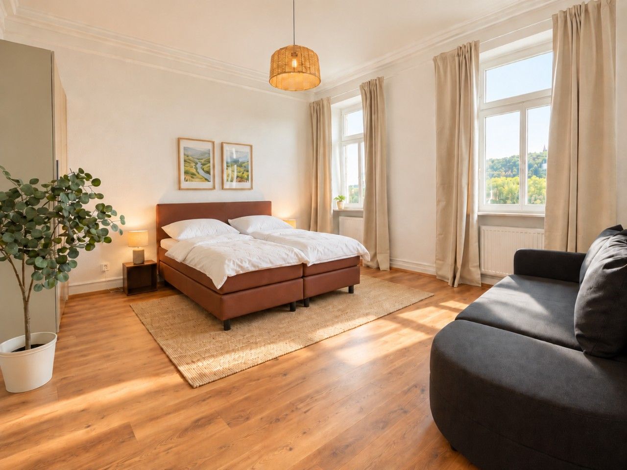 Ein Schlafzimmer mit einem Bett, einem Sofa, einer Zimmerpflanze und einem Fenster mit Vorhängen.