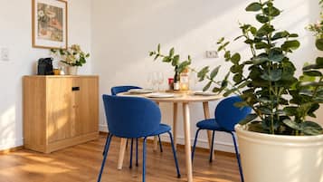 A dining area with a wooden cabinet, blue chairs, a round table, and a potted plant.