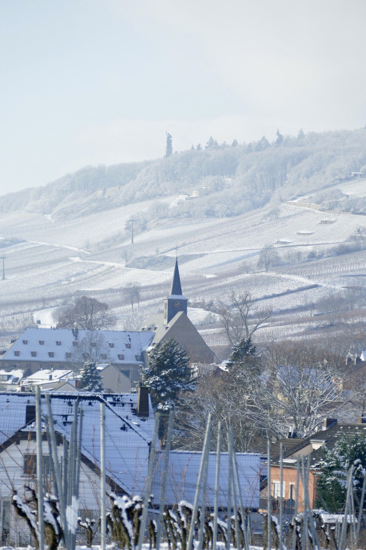 Eine verschneite Landschaft mit einer Kirche und Wohnhäusern.