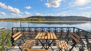 Un espace extérieur aménagé avec une table et des bancs, offrant une vue sur un plan d’eau.
