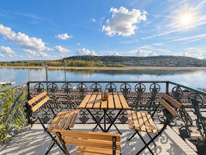 Un espace extérieur aménagé avec une table et des bancs, offrant une vue sur un plan d’eau.