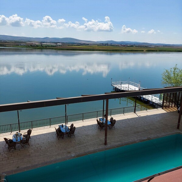 A pool area with a view of a calm lake and distant hills.