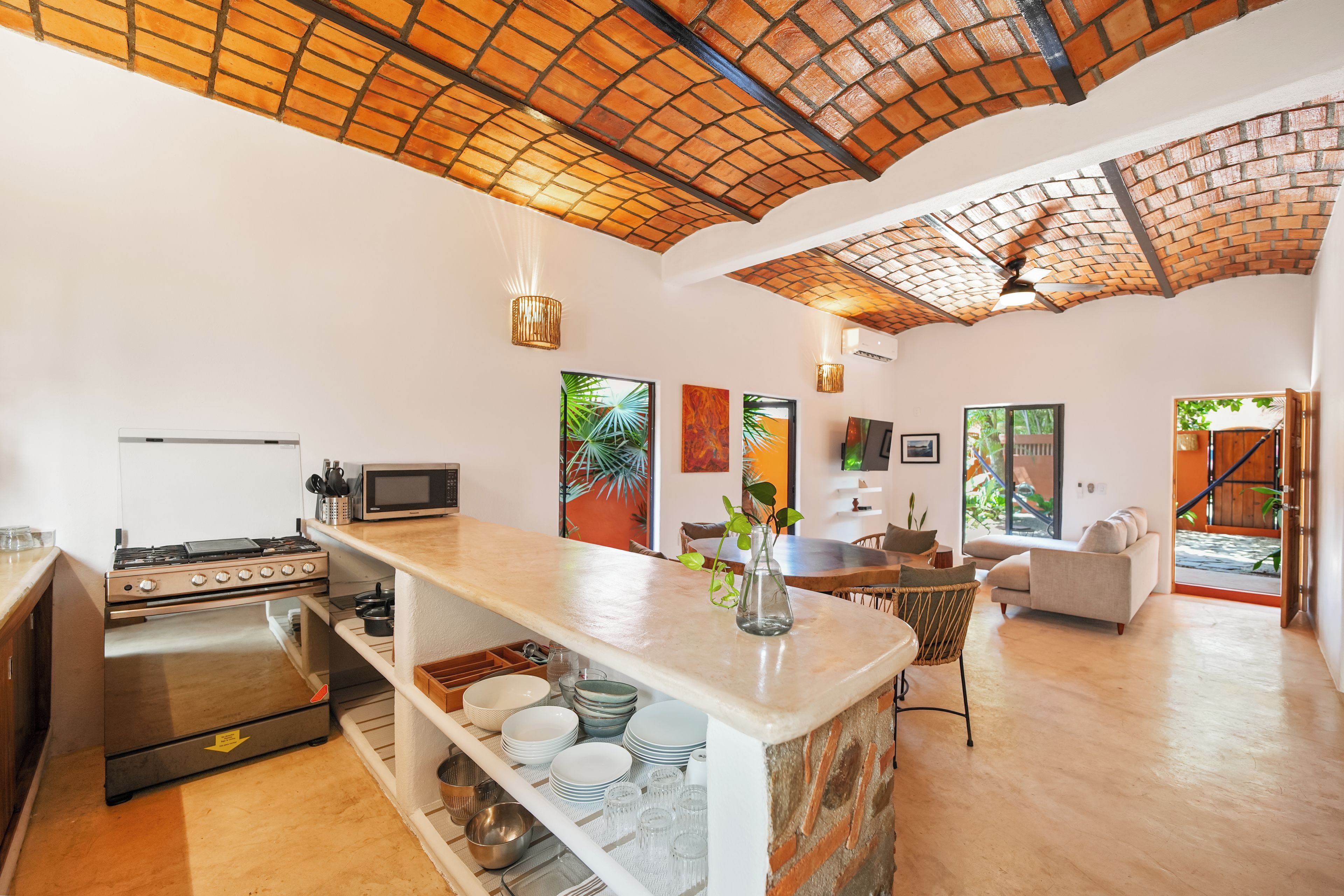 Una cocina amplia con una isla central, un comedor con vistas y una sala de estar con sofá y televisor.