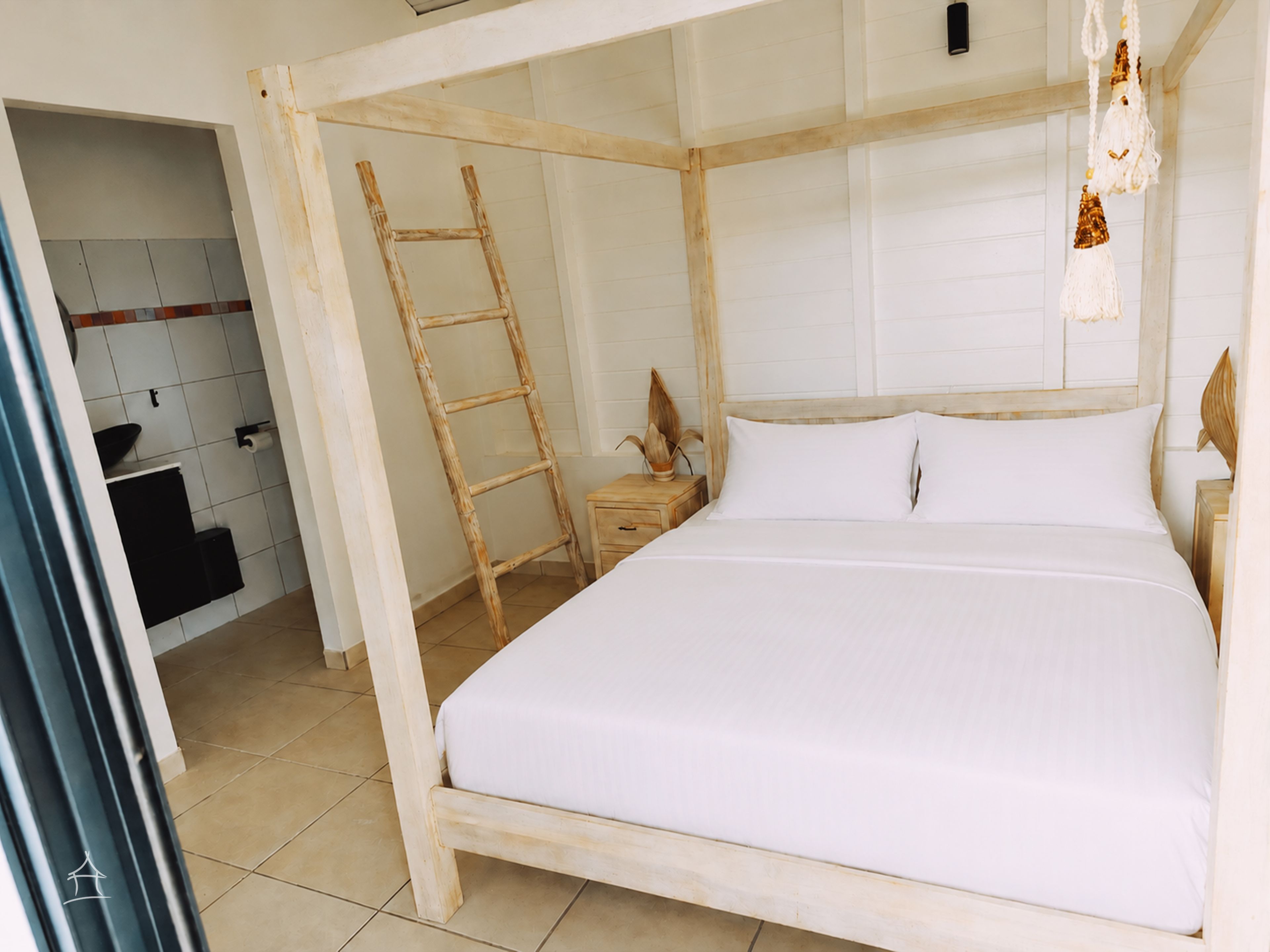 A room with a wooden bed frame, a ladder, a bedside table, and a white wall.