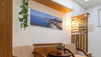 Uma sala de estar moderna com sofá de madeira, uma mesa redonda pequena e um vaso de planta.