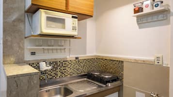 A compact kitchen with a built-in microwave, a sink, and a stove.