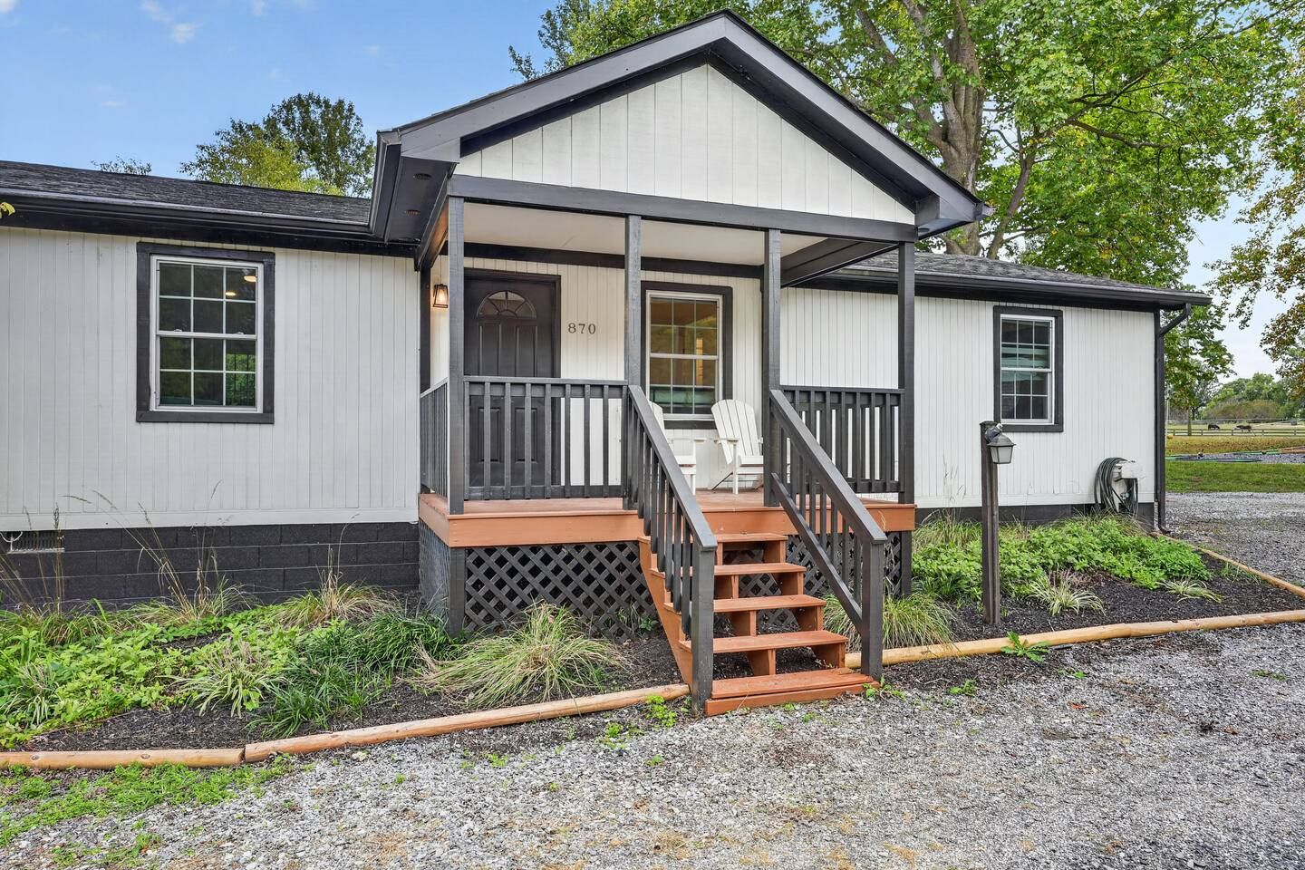 A single-story building with a porch, a set of stairs leading to the entrance, and a mailbox.
