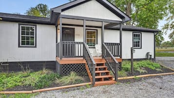 A single-story building with a porch, a set of stairs leading to the entrance, and a mailbox.