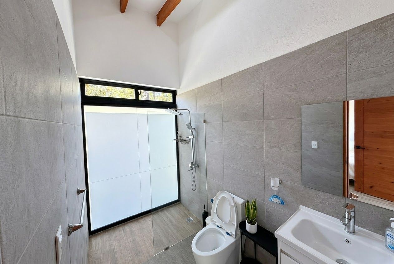 Ein modernes Badezimmer mit Dusche, Toilette, Waschbecken und einem großen Spiegel.