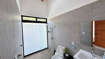 Ein modernes Badezimmer mit Dusche, Toilette, Waschbecken und einem großen Spiegel.