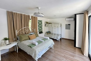 Un dormitorio con una cama, una mesita de noche, una planta colgante y una cama litera.