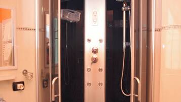 Una cabina doccia con pareti in vetro, un soffione a mano, un pannello di controllo e un water.