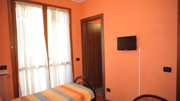 Una stanza con un letto, una sedia, una televisione a muro e una porta.