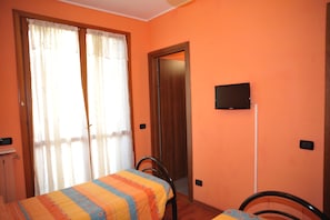 Una habitación con cama, una silla, televisor montado en la pared y una puerta.