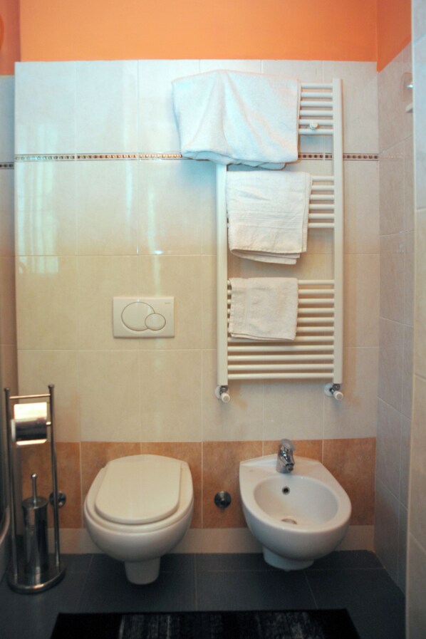 Un baño con inodoro, bidé y perchero para toallas.