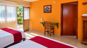 A hotel room with two beds, a desk, a chair, and a door. - Hotel El Trebol (Yautepec)