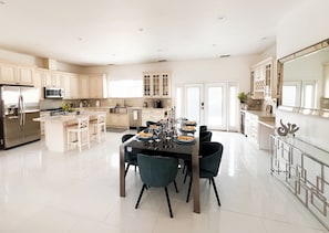 A spacious kitchen with modern appliances, a dining area with a table set for four, and a large mirror reflecting the space. - Resort Style Compound with detached Casita & Pool (Los Angeles)