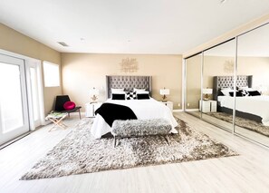 A modern bedroom with a large bed, a fluffy rug, a bench, and a chair. - Resort Style Compound with detached Casita & Pool (Los Angeles)