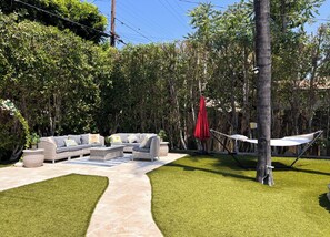 Un patio con un sofá, un paraguas rojo y una hamaca.