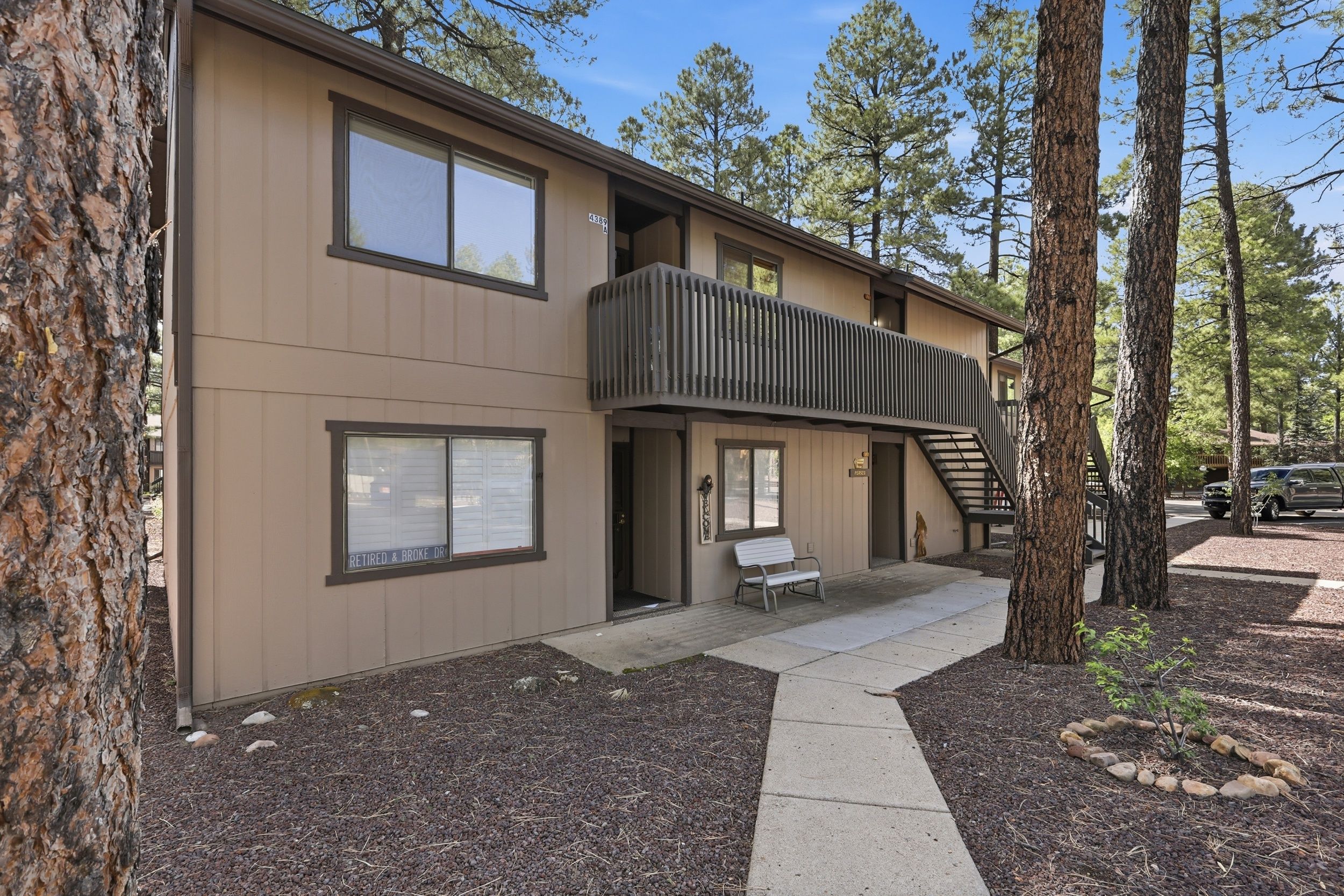 A two-story building with a balcony, a bench, and a paved walkway.
