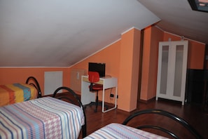 Una habitación con dos camas, un escritorio con silla, un armario y una puerta.