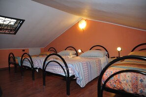 A dormitory room with four beds, each with a headboard and a bedside lamp. - New Listing (Pero)