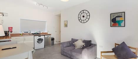 A modern living space with a kitchen, a dining area, and a seating area with a sofa and a chair.