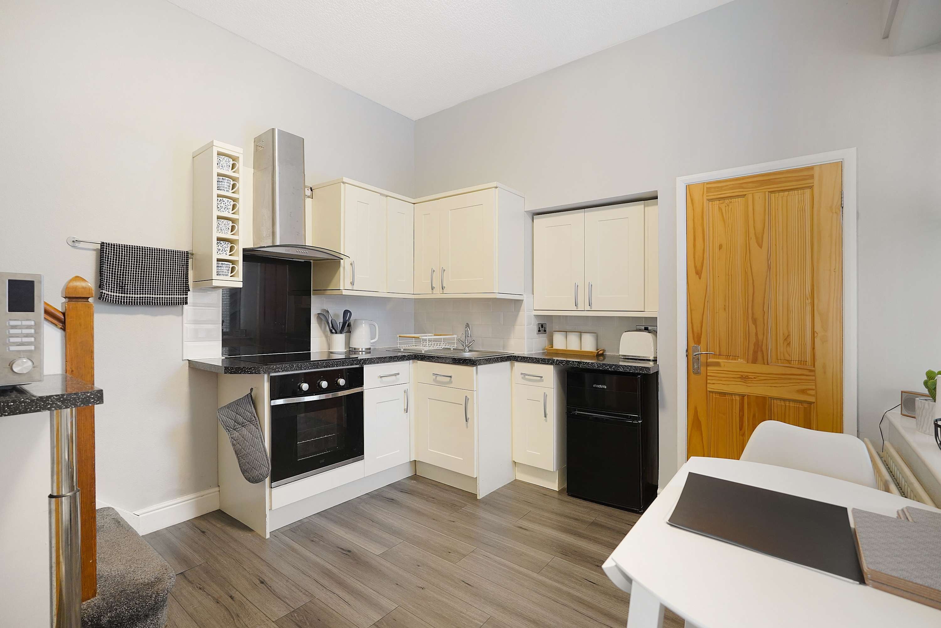 Una cocina compacta con estufa, horno, lavavajillas y una puerta de madera.