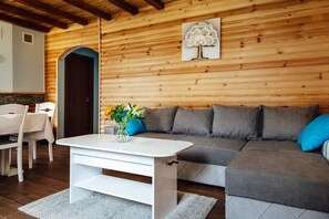 En moderne stue med et hvidt sofabord, grå sofa og en trævæg med et trækunstværk.