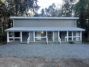 En toetages bygning med en overdækket veranda og en grusbelagt indkørsel.