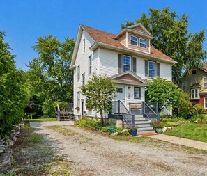 A two-story house with a front porch, a driveway, and a garden.