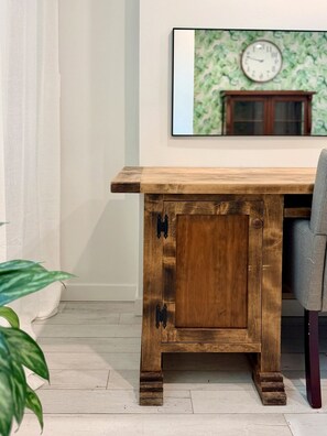 Una mesa de comedor de madera con un aparador, una silla, una planta en maceta y un reloj en la pared.