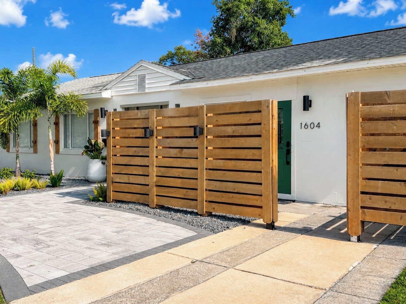 A modern house with a white exterior, a green door, and a wooden fence.