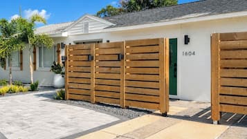 A modern house with a white exterior, a green door, and a wooden fence.