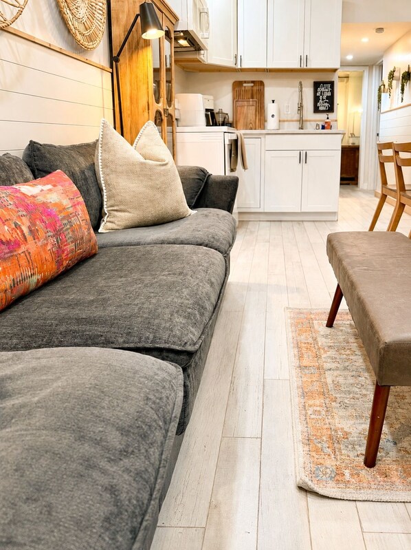 A modern living room with a grey sofa, a patterned rug, and a wooden coffee table.