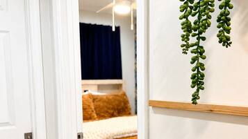 Une chambre avec un lit, un ventilateur de plafond et une plante suspendue.