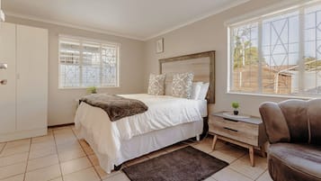Een slaapkamer met een bed, nachtkastje en een raam.