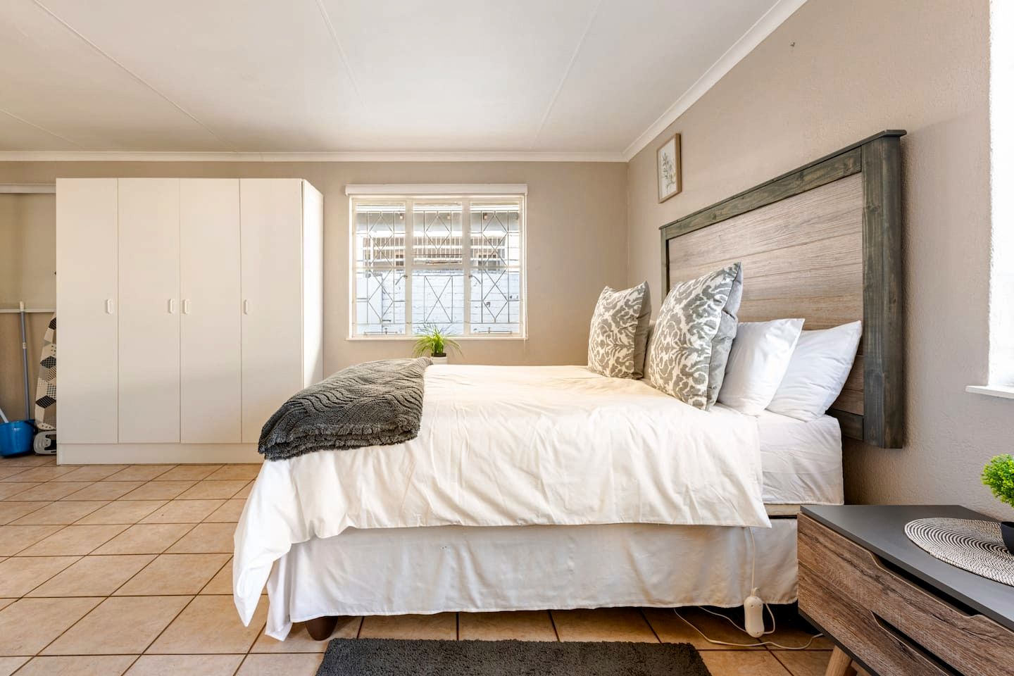 Un dormitorio con cama, mesita de noche, ventana con vistas y armario.