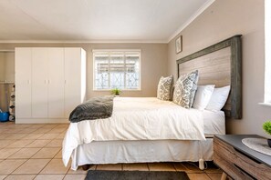 A bedroom with a bed, a bedside table, a window with a view, and a wardrobe. - Charming Self-catering Apartment in Brackendowns, Alberton (Alberton)