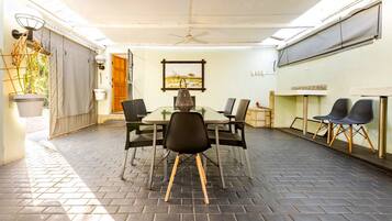 Un patio cubierto con mesa y sillas, un ventilador de techo y vistas al exterior.
