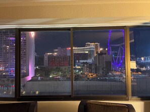 Vista desde la ventana de un hotel sobre un paisaje urbano nocturno con edificios iluminados y un estacionamiento.