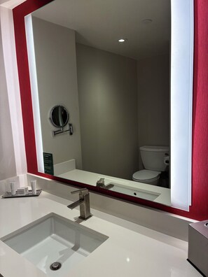 Une salle de bain avec un lavabo blanc, un miroir et des toilettes.